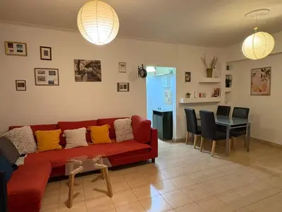 a living room with a red couch and a table at Cozy lower ground floor apartment by Sea and Tram in Athens
