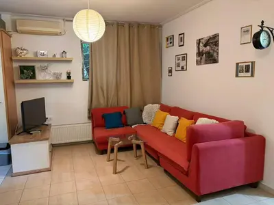 a living room with a red couch and two chairs at Cozy lower ground floor apartment by Sea and Tram in Athens