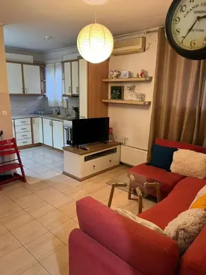 a living room with a red couch and a clock at Cozy lower ground floor apartment by Sea and Tram in Athens