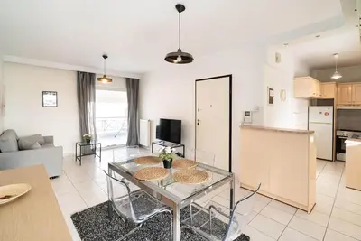 a living room with a glass table and a kitchen at La Casa De Los Dioses Athens in Athens