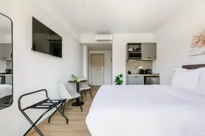 a bedroom with a large white bed and a kitchen at B48 Athens Dafni in Athens