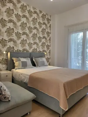 a bedroom with a large bed and a window at Green apartment-center of Varkiza resort in Vari