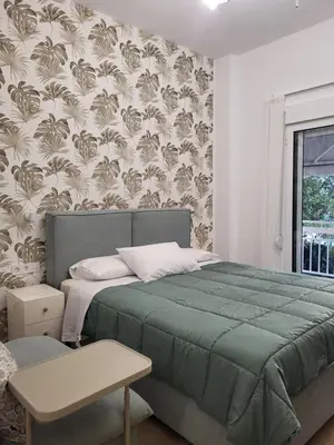 a bedroom with a bed with a green blanket at Green apartment-center of Varkiza resort in Vari