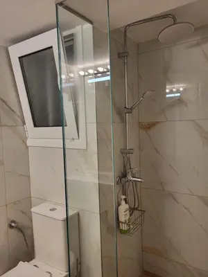a bathroom with a glass shower with a toilet at Green apartment-center of Varkiza resort in Vari