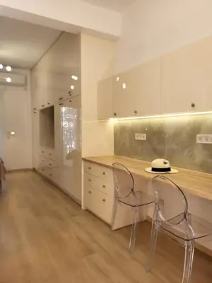 a kitchen with two chairs and a counter with cabinets at Green apartment-center of Varkiza resort in Vari
