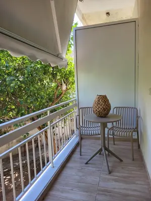 two chairs and a table on a balcony at Green apartment-center of Varkiza resort in Vari