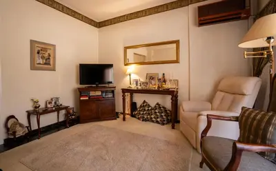 a living room with a chair and a television at 15' to Sea & Acropolis in Athens