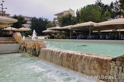 a swimming pool with a water fountain in a resort at 15' to Sea & Acropolis in Athens