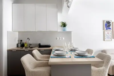a kitchen with a table and chairs and a kitchen with white cabinets at Les Nuances de Bleu - 1-Bedroom & Balcony in Athens in Athens
