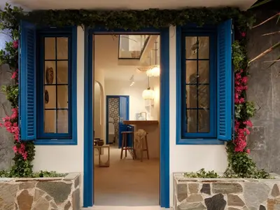 a house with blue windows and flowers on the facade at Athens Cycladic Hideaway in Athens