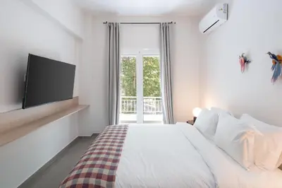 a white bedroom with a bed and a tv at 1BR Next to Metro Modern Living & Arcade Machine in Athens