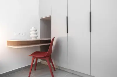 a red chair in a room with white cabinets at 1BR Next to Metro Modern Living & Arcade Machine in Athens