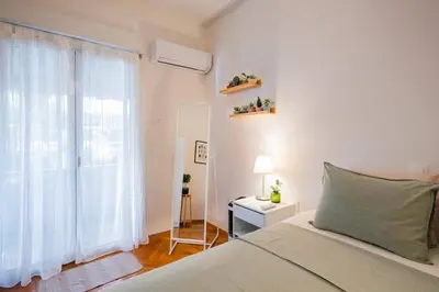 a white bedroom with a bed and a window at Athens Retreat Paleo Faliro,Onassis,REA Hospital in Athens