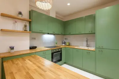 a green kitchen with wooden floors and green cabinets at Nea Smyrni Square Appartment in Athens