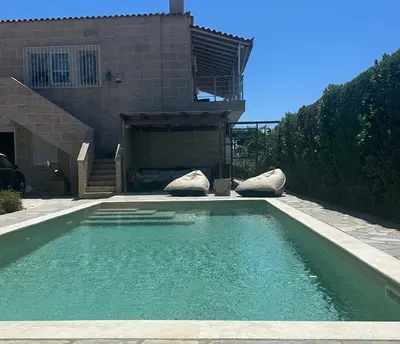 a swimming pool with two pillows in front of a house at Villa Agia Marina 5m walk to the beach with private pool in Aghia Marina