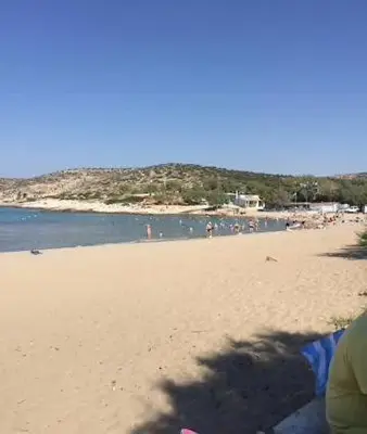 a sandy beach with people in the water at Villa Agia Marina 5m walk to the beach with private pool in Aghia Marina