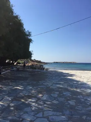 a person standing on a beach near the water at Villa Agia Marina 5m walk to the beach with private pool in Aghia Marina