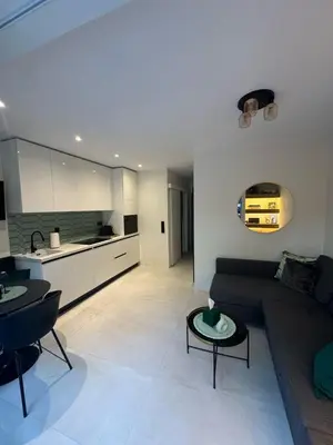 a living room with a couch and a kitchen at Cosy apartment with shared pool and garden in Athens