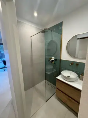 a bathroom with a glass shower and a sink at Cosy apartment with shared pool and garden in Athens