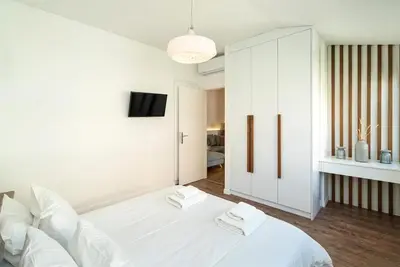 a white bedroom with a white bed and a tv at Altezza Terrazza Athens in Athens