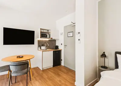 a small room with a table and a bed and a kitchen at Limehome Piraeus Iris in Piraeus