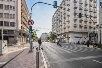 a city street with a green traffic light and buildings at Limehome Piraeus Iris in Piraeus