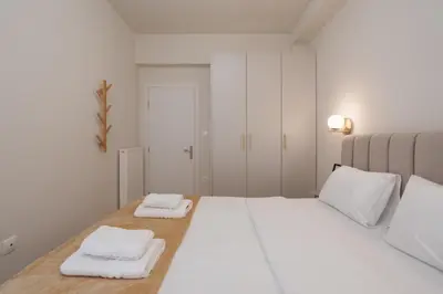 a white bedroom with two white towels on a bed at Acropolis Retreat Walk to Museum in Athens