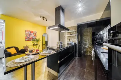 a kitchen with yellow walls and black countertops at Two bedroom Lux apartment Next to the metro in Athens