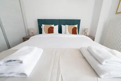 a bed with white sheets and towels on it at Stylish Apartment in Piraeus -F9 in Piraeus