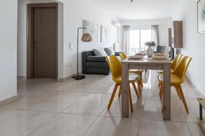 a dining room and living room with a table and yellow chairs at Stylish Apartment in Piraeus -F9 in Piraeus