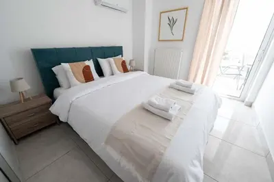 a white bedroom with a large bed and a window at Stylish Apartment in Piraeus -F9 in Piraeus