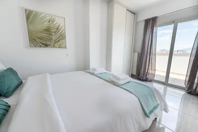 a white bedroom with a bed and a large window at Top-Floor Retreat in Piraeus-H5 in Piraeus