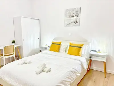 a white bedroom with a large bed with yellow pillows at Alimos Apartment near Edem Beach and the Sea with 2 Bedroom in Athens