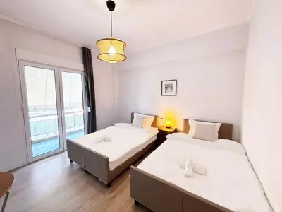 two beds in a room with a large window at Alimos Apartment near Edem Beach and the Sea with 2 Bedroom in Athens
