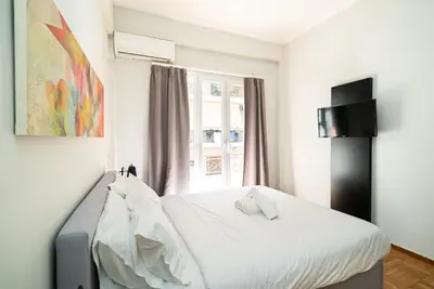 a bedroom with a bed with white sheets and a window at Acropolis Anemone Apartment in Athens