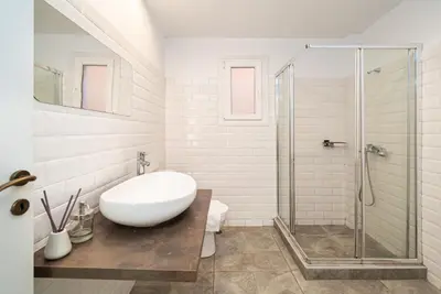 a bathroom with a sink and a glass shower at Acropolis Anemone Apartment in Athens