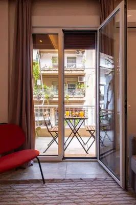 a room with a sliding glass door with a table on a balcony at Stylish 2BDR Exarchia Apt with Balcony and Workspace in Athens