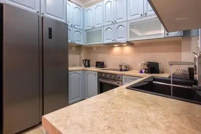 a kitchen with white cabinets and a stainless steel refrigerator at Stylish 2BDR Exarchia Apt with Balcony and Workspace in Athens