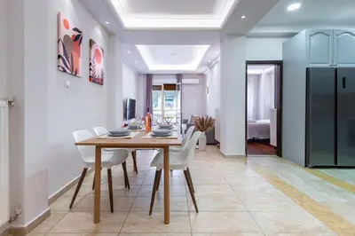 a dining room with a wooden table and white chairs at Stylish 2BDR Exarchia Apt with Balcony and Workspace in Athens