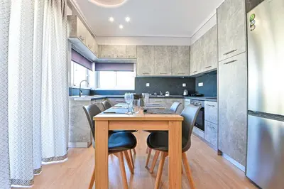 a kitchen with a wooden table and black chairs at Elegant Sea View Stay - Piraeus Port in Piraeus