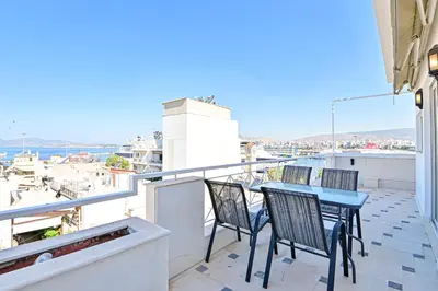 a balcony with three chairs and a table on a roof at Elegant Sea View Stay - Piraeus Port in Piraeus