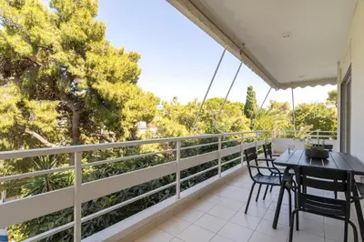 a balcony with a table and chairs and trees at Cozy & Renovated, Walk to beach in Athens