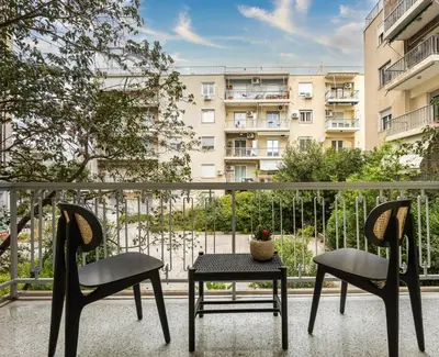 a balcony with two chairs and a table and a building at Attica Skyline Living! in Athens