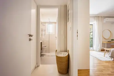 a hallway with a bathroom with a toilet and a chair at Attica Skyline Living! in Athens