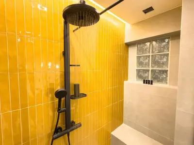 a shower in a bathroom with yellow tiles at Syntagma Spacious Residence in Athens