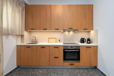 a kitchen with wooden cabinets and a sink at Stylish Retreat in Quiet Piraeus Newly Renovated in Piraeus