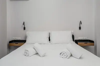 a white bed with white sheets and pillows at Stylish Retreat in Quiet Piraeus Newly Renovated in Piraeus