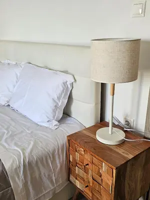 a lamp on a wooden table next to a bed at Olive Ridge in Porto Rafti