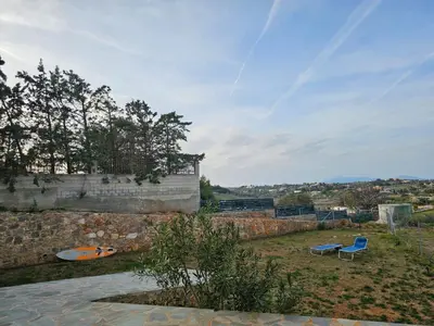 a stone wall with two blue chairs in a yard at Olive Ridge in Porto Rafti