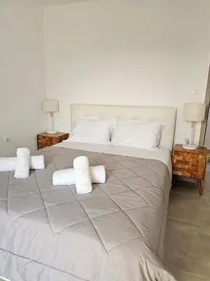 a large bed with white sheets and pillows on it at Olive Ridge in Porto Rafti